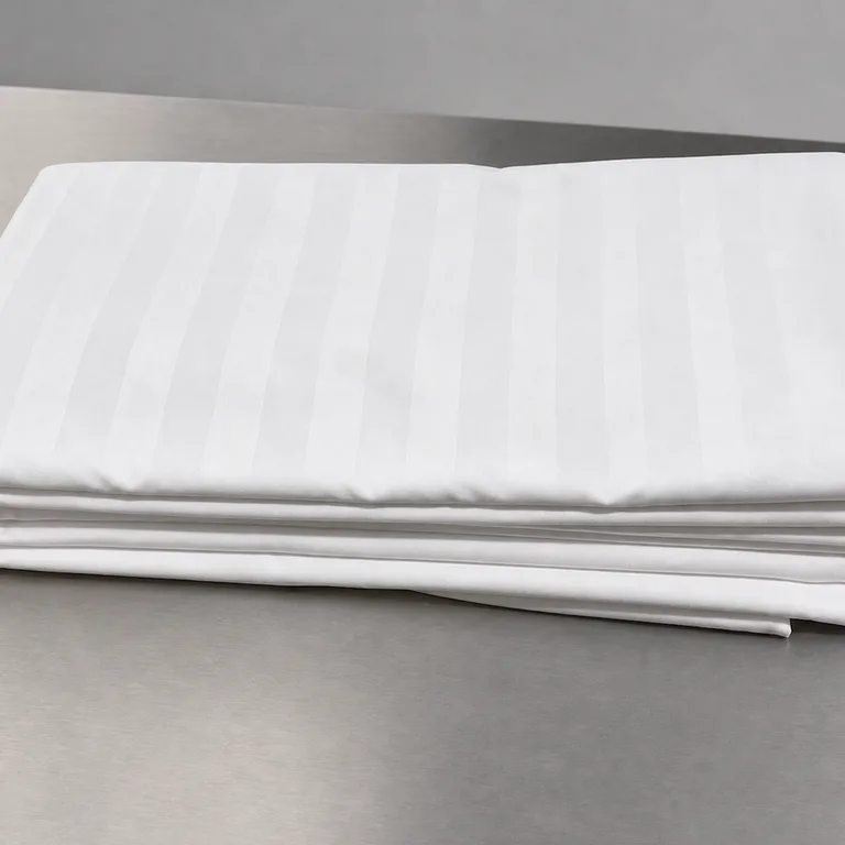 Folded white satin-stripe doona covers on a stainless bench