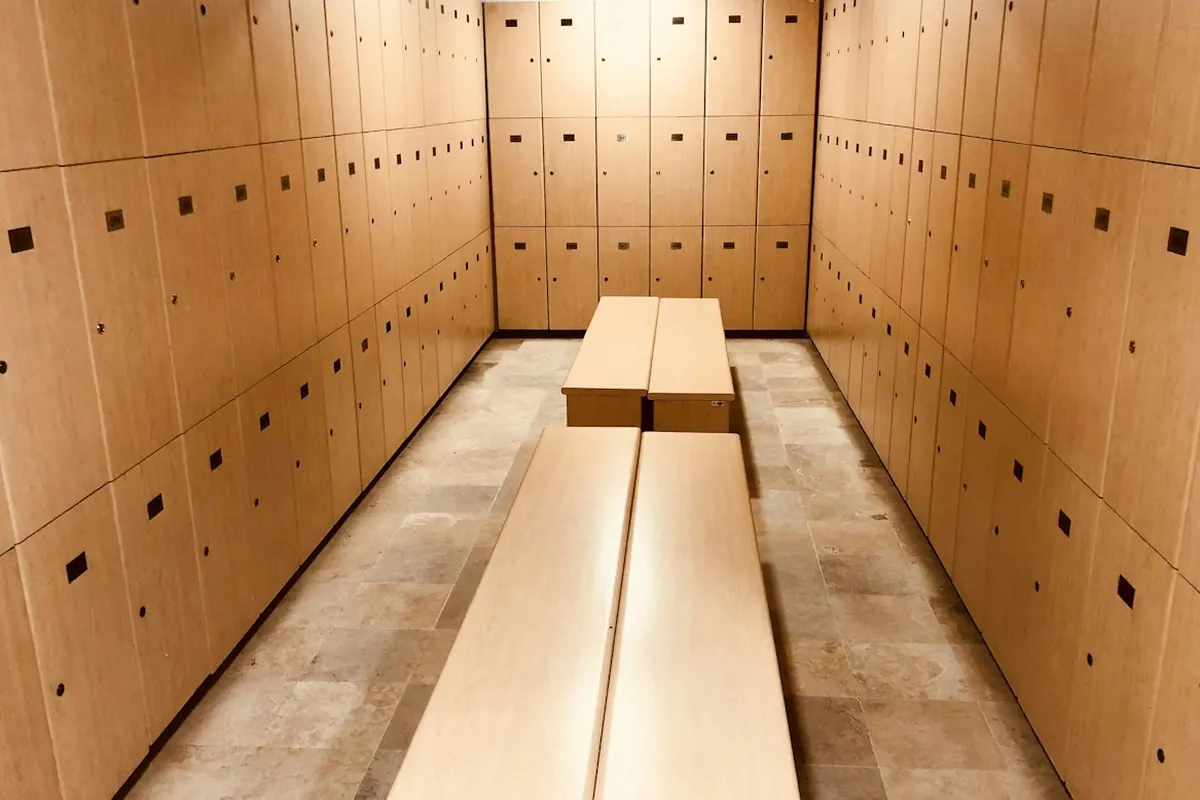 Changing room with rows of wooden lockers and a long central bench