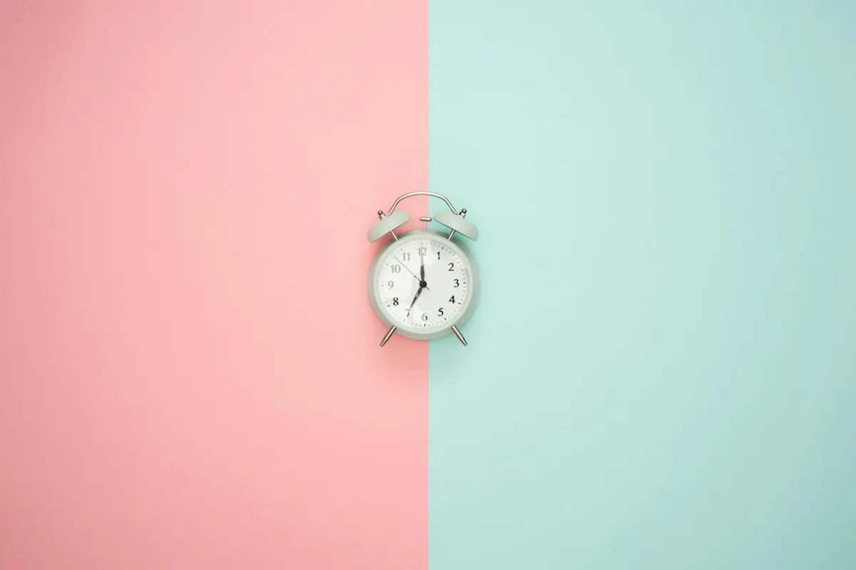 Alarm clock against a pink and mint background