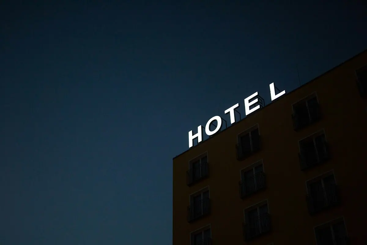 Hotel sign on top of a building against a dark sky