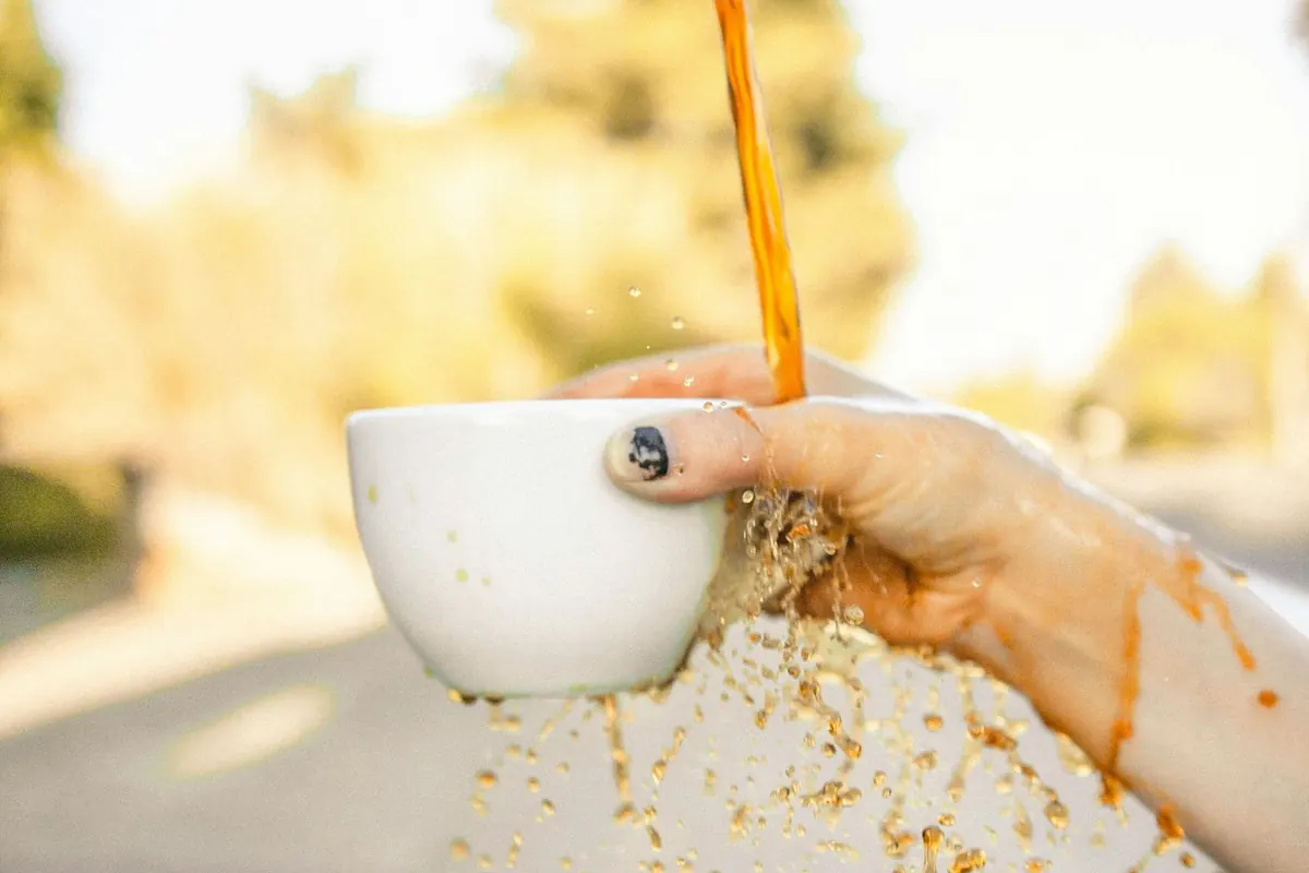 Coffee spilling from a cup held outdoors