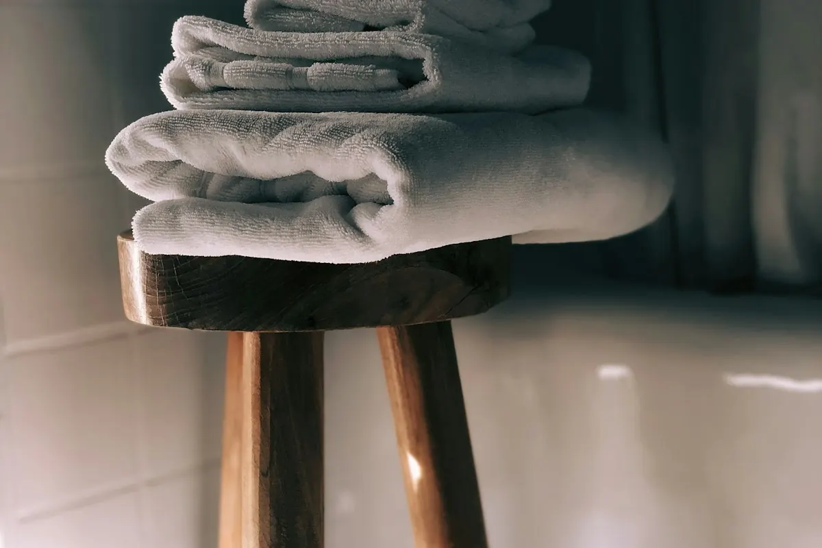 Folded towels on a small wooden stool in a bathroom