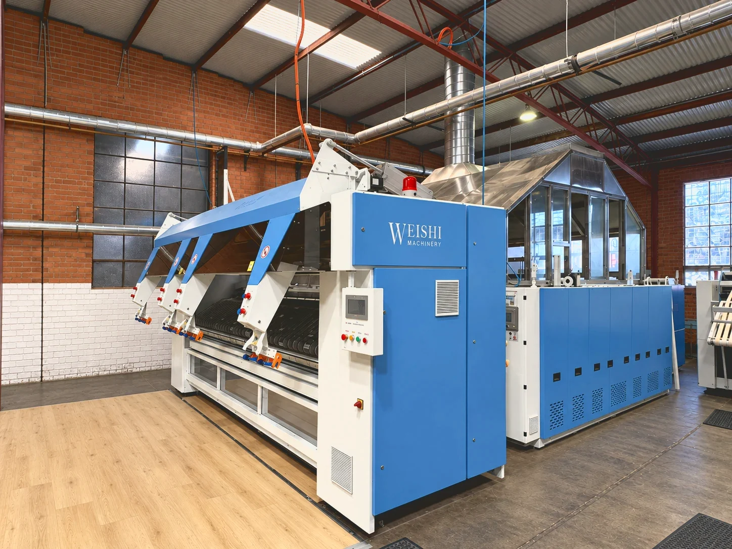 The blue WEISHI flatwork ironing line at the eWASH laundry