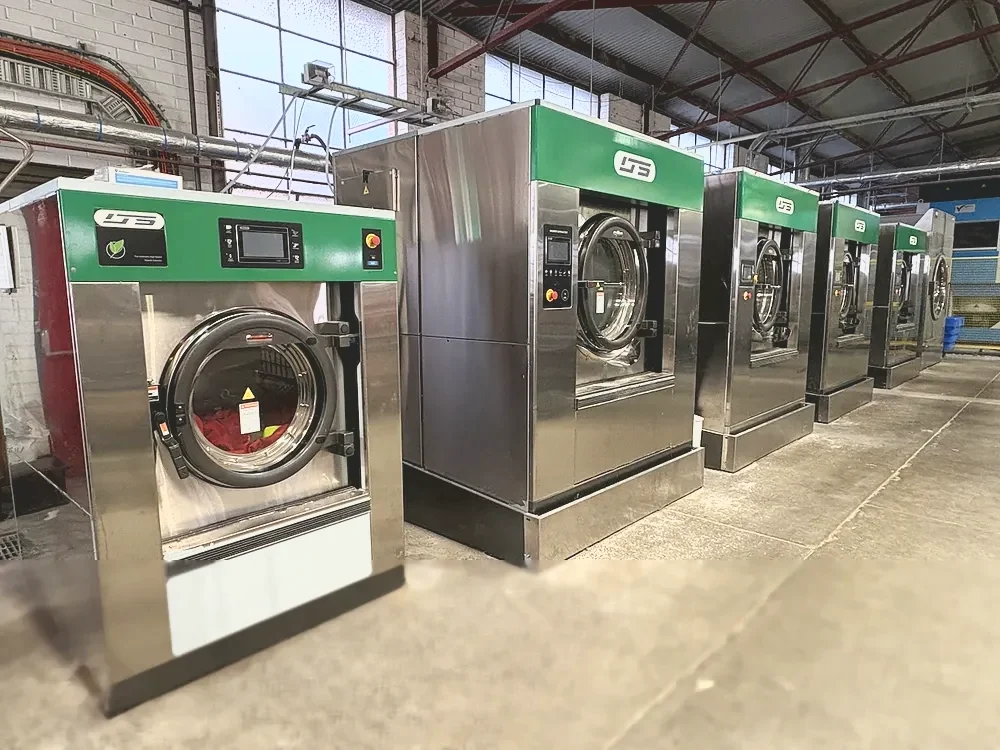 A row of industrial washer-extractors at the eWASH laundry